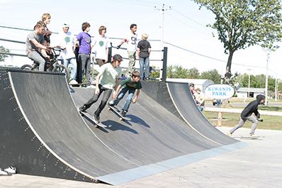 Kiwanis Park - Several youth skateboarding down ramp
